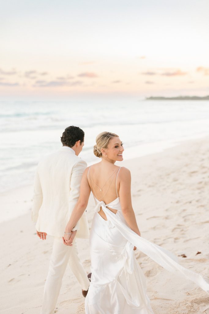 Couple walking on Tulum beach at sunset, captured by a destination wedding photographer in Tulum, Mexico.