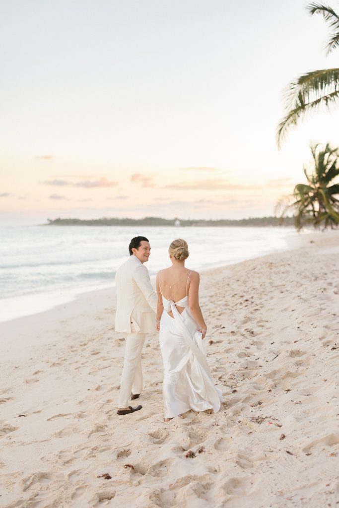 Couple walking on Tulum beach at sunset, captured by a destination wedding photographer in Tulum, Mexico.