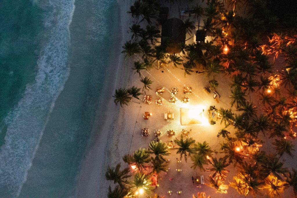 Aerial view of a Tulum beach wedding ceremony at sunset, captured by a destination wedding photographer using drone photo