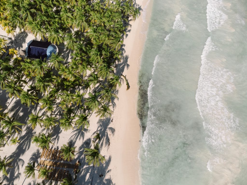 Aerial view of a Tulum beach wedding ceremony at sunset, captured by a destination wedding photographer using drone photo