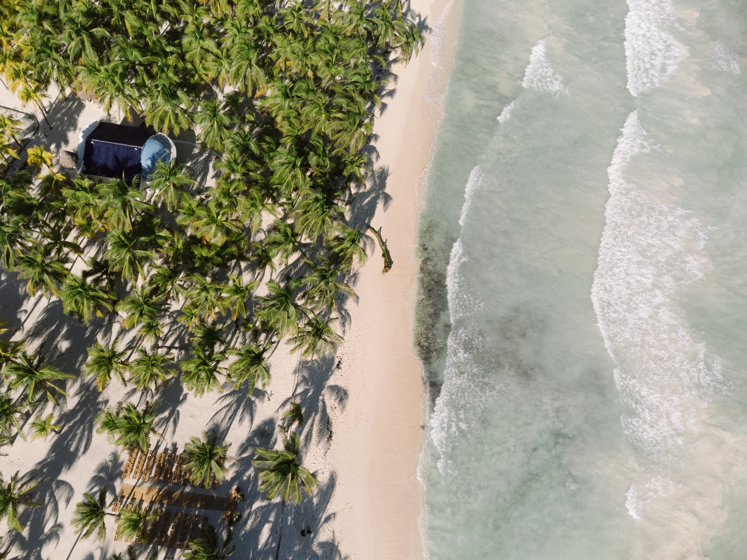 Aerial view of a Tulum beach wedding ceremony at sunset, captured by a destination wedding photographer using drone photo
