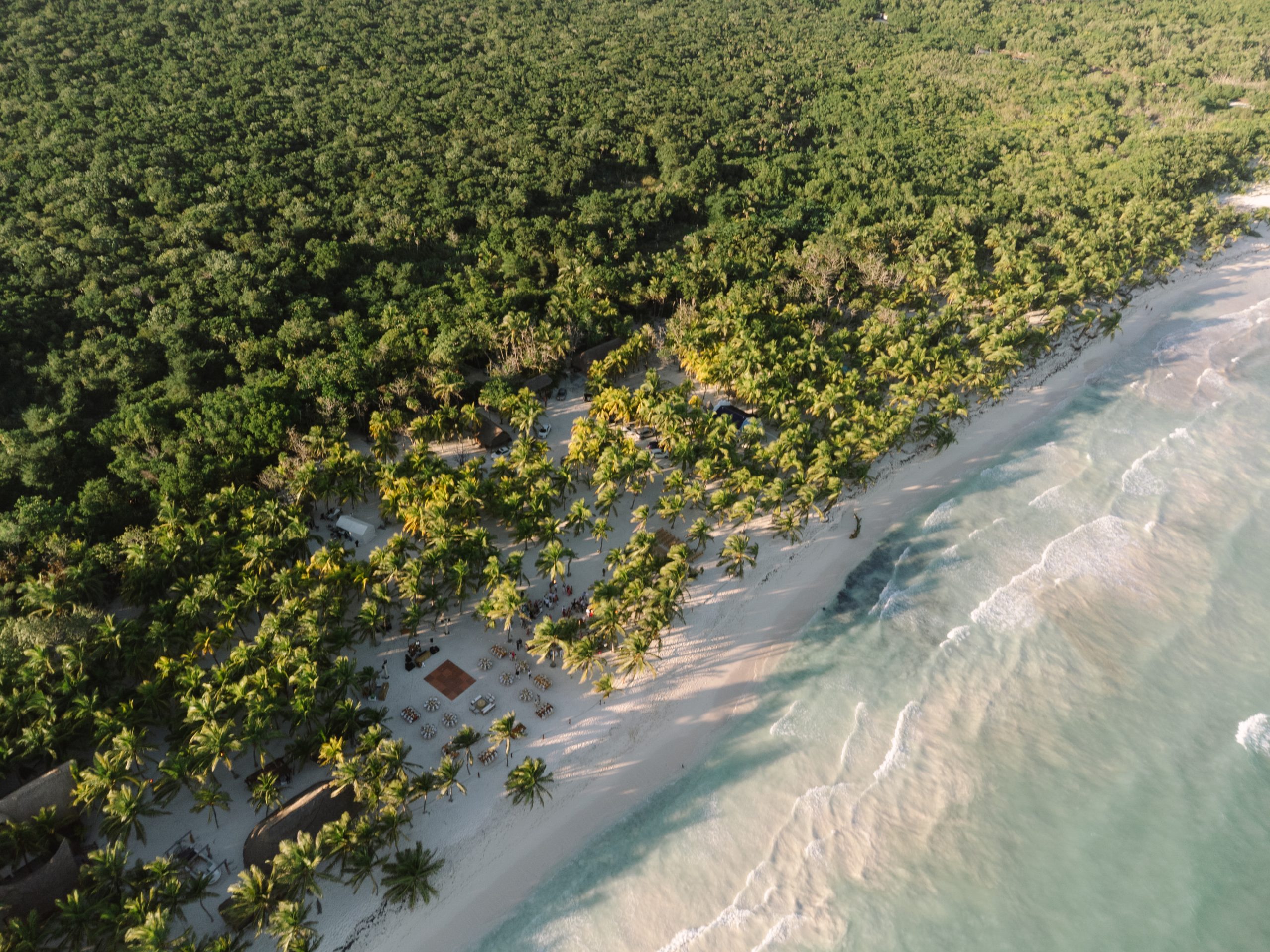 Aerial view of a Tulum beach wedding ceremony at sunset, captured by a destination wedding photographer using drone photo