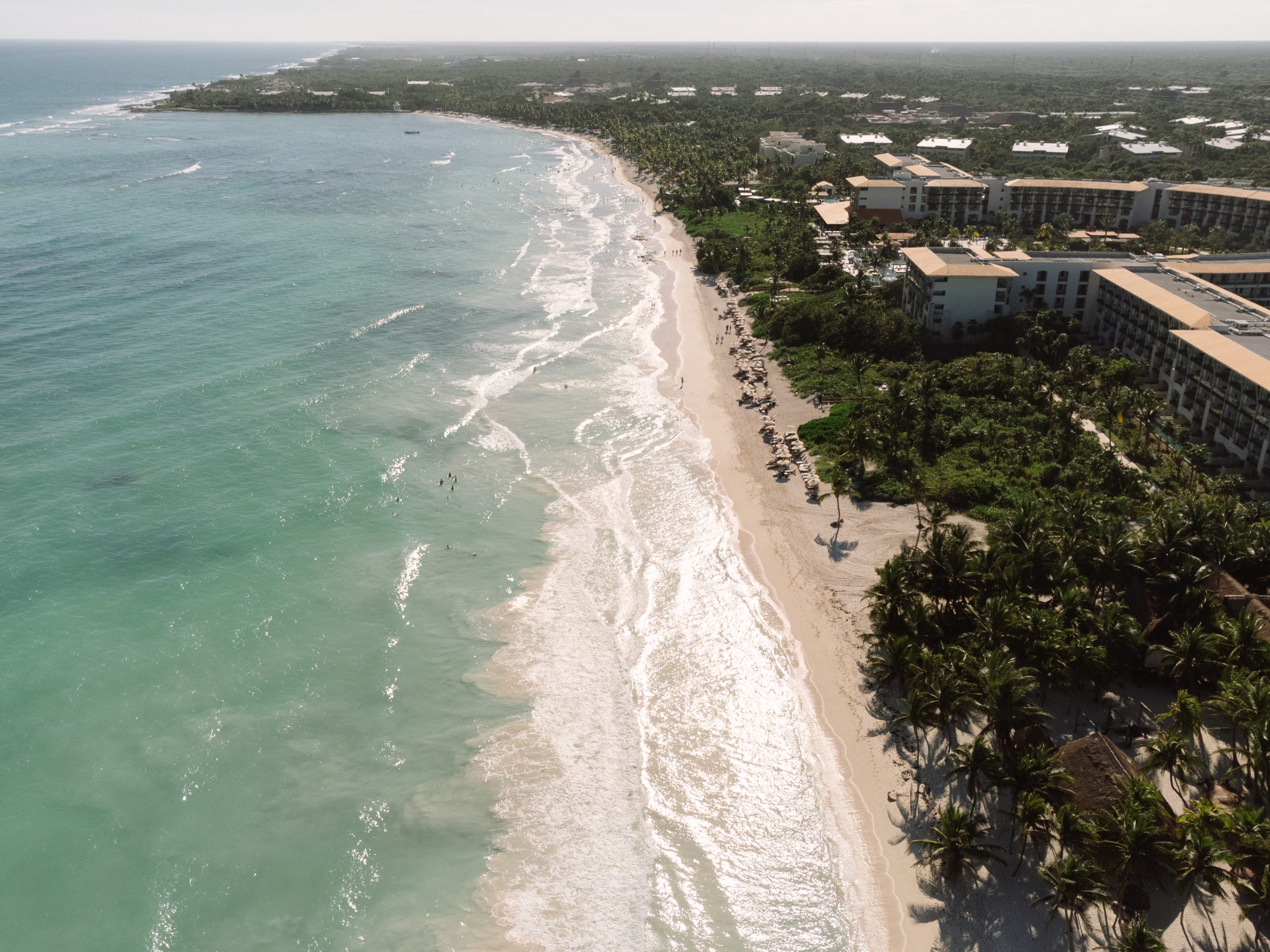 Aerial view of a Tulum beach wedding ceremony at sunset, captured by a destination wedding photographer using drone photo