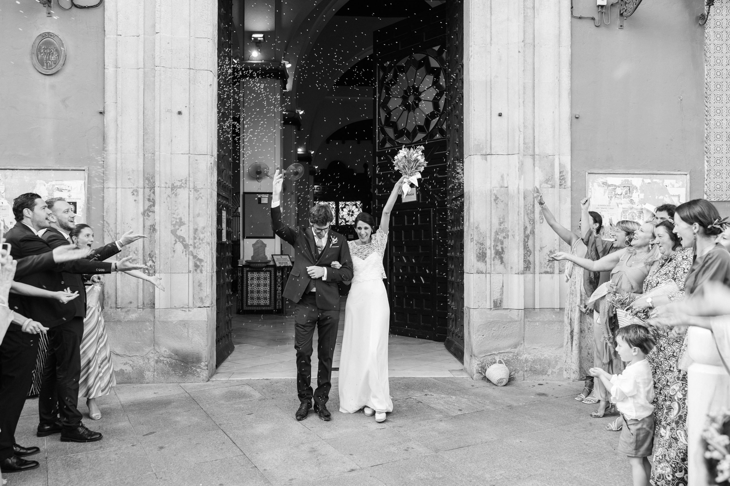 Salida de los novios bajo lluvia de pétalos tras casarse en San Lorenzo.