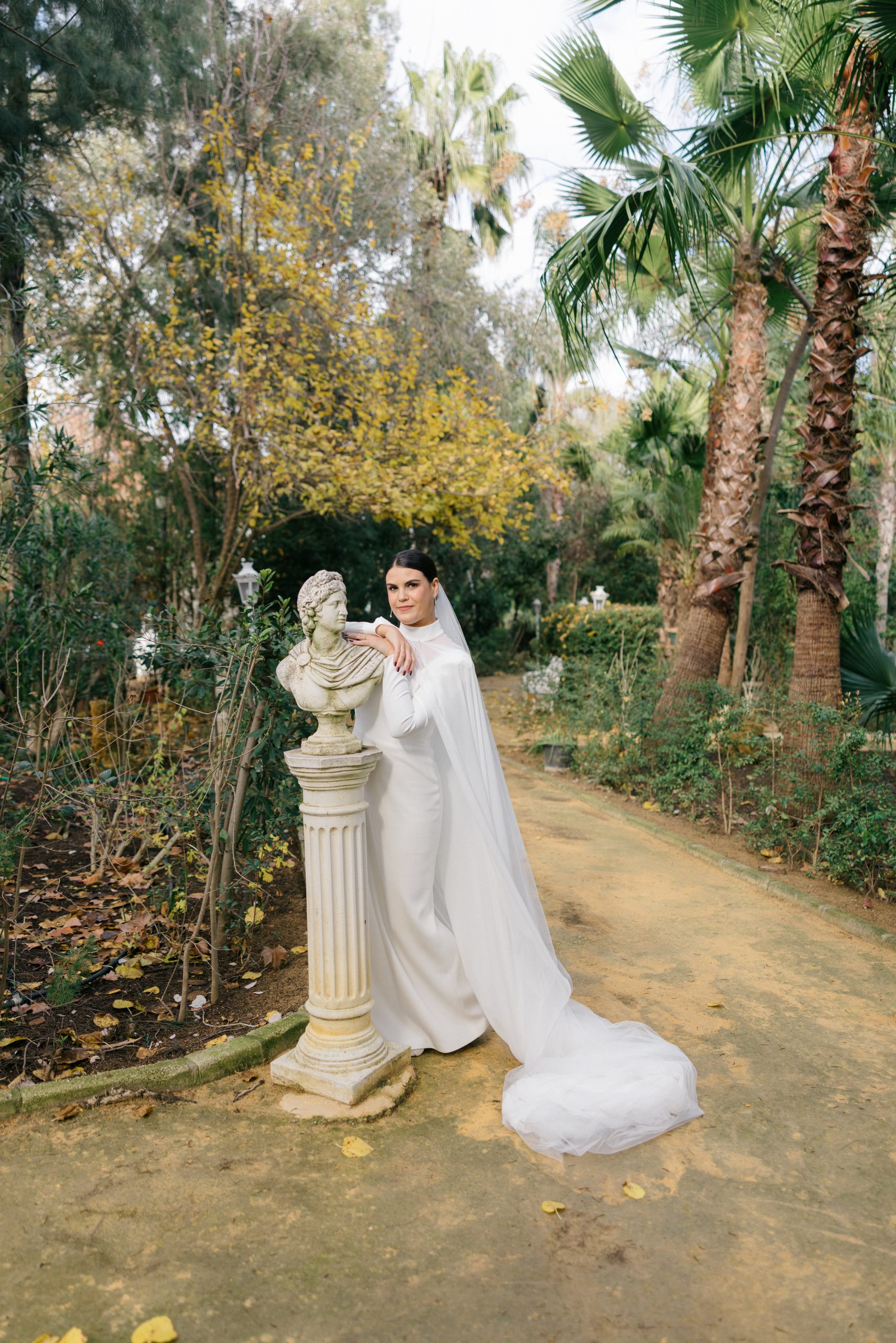 Retrato de novia junto a busto clásico en jardines de Finca Santa Clotilde