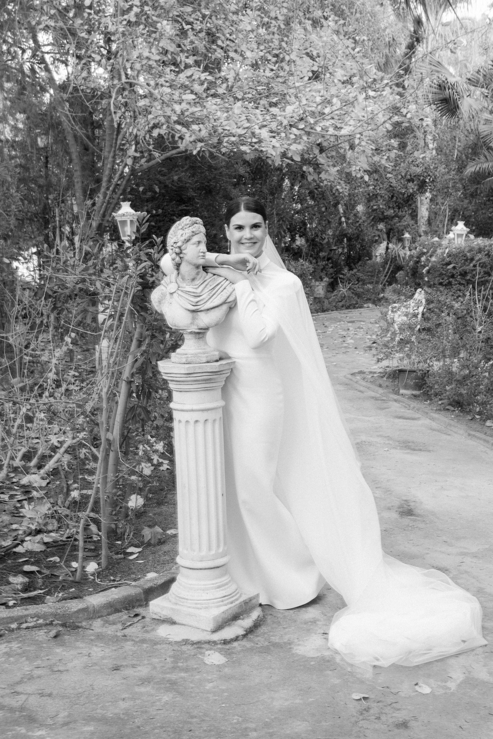 Retrato de novia junto a busto clásico en jardines de Finca Santa Clotilde